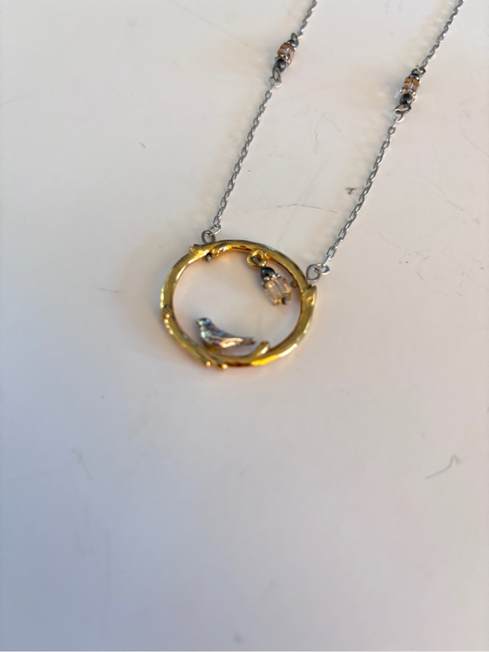 Brighton necklace featuring a circular branch-style pendant with perched bird.